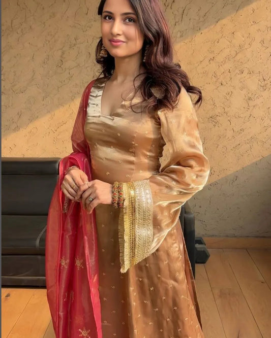 Woman wearing a traditional outfit with a red dupatta indoors.