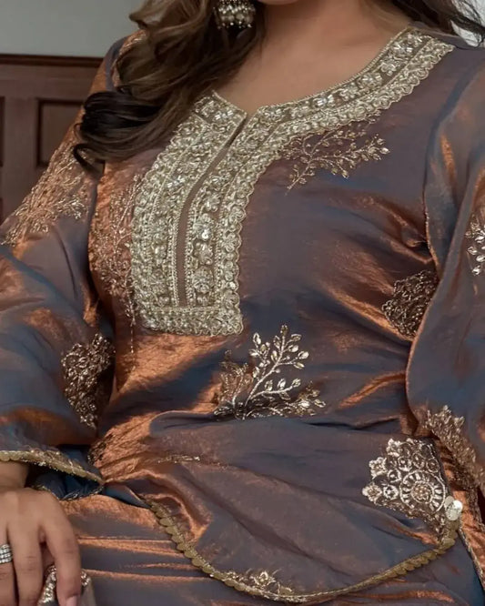 Close-up of a brown traditional outfit with intricate gold embroidery.