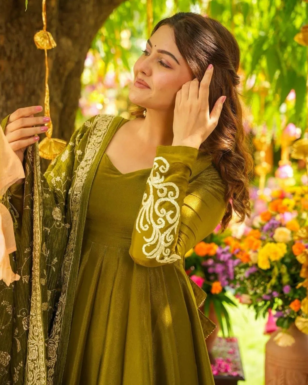 Woman in a green chiffon suit traditional outfit with floral decorations in the background