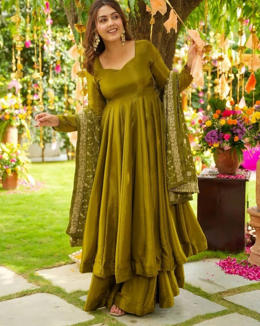 Woman in a green chiffon suit traditional outfit with floral decorations in the background