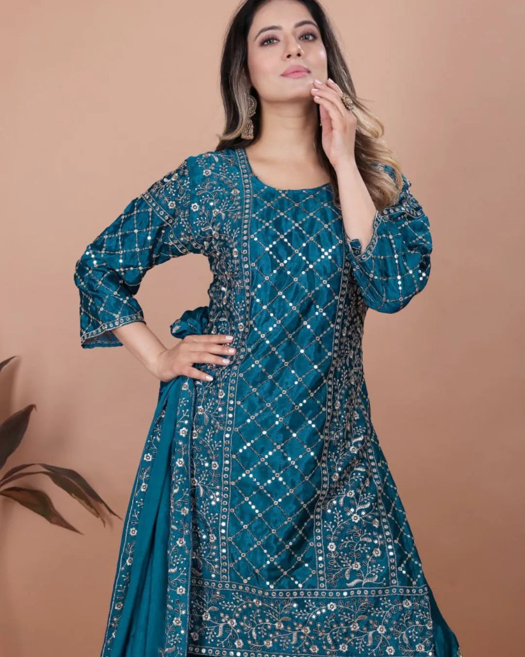 Woman wearing a blue embroidered traditional outfit against a beige background