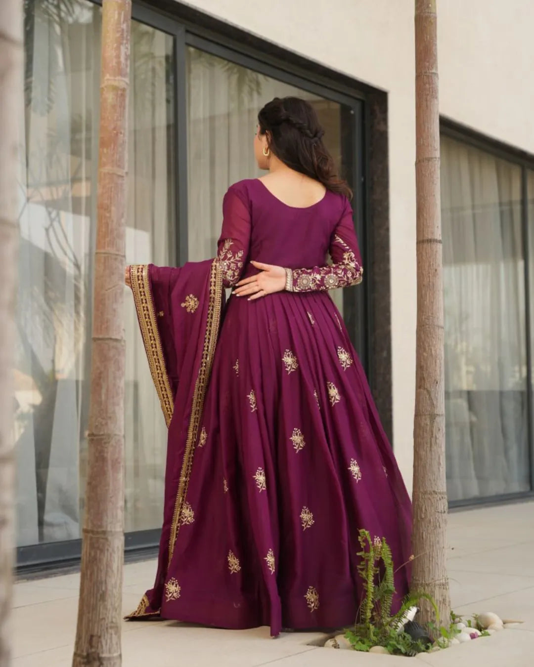 Woman in a purple embroidered traditional outfit standing outdoors.