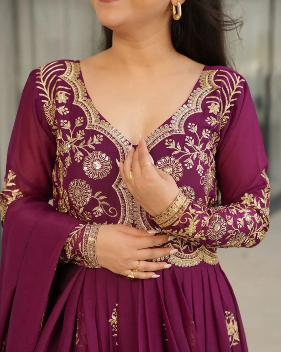Purple traditional outfit with gold embroidery on a neutral background