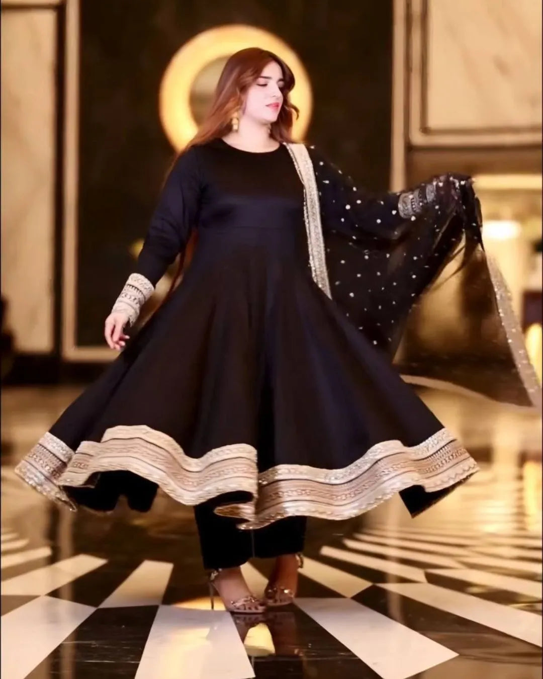 Woman in a black dress with gold trim dancing in a decorated room.