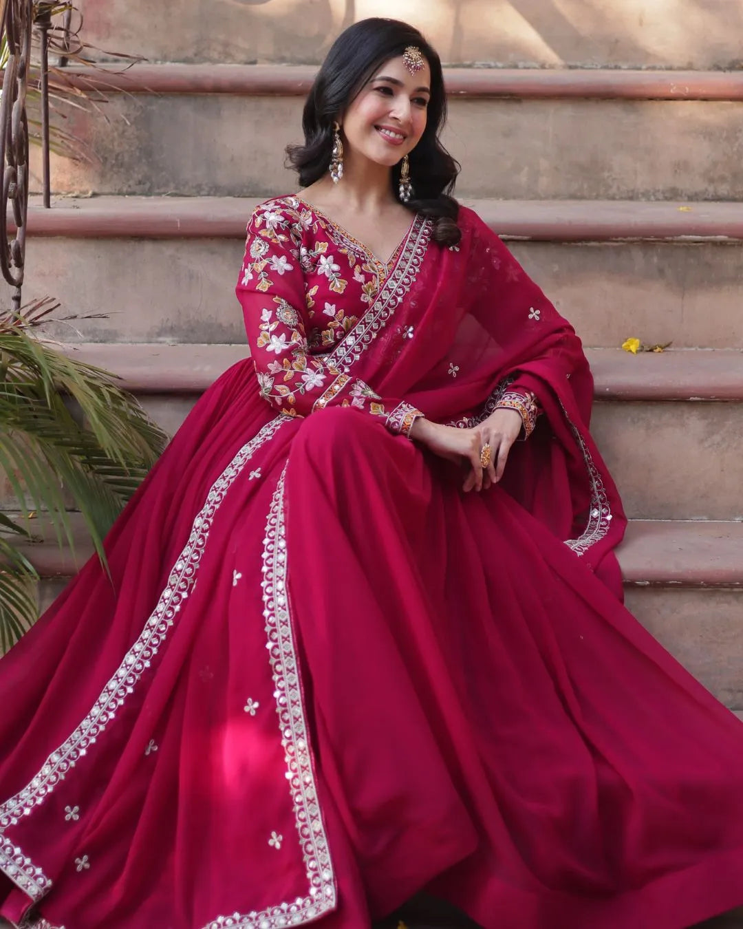 Woman in a red Suit with floral patterns sitting on steps.