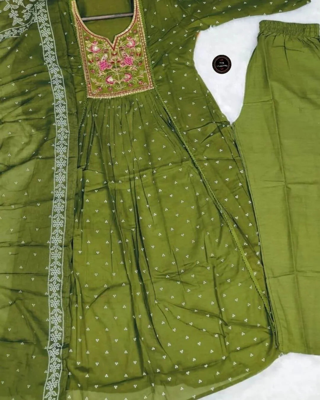 Green traditional outfit with embroidered top and matching pants on a white background
