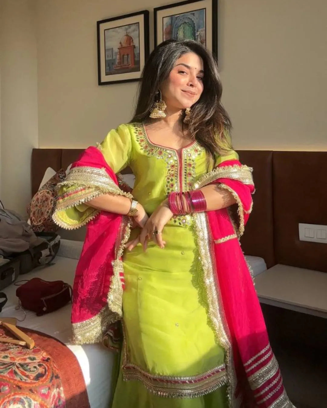 Woman in a bright green suit outfit with pink dupatta indoors.