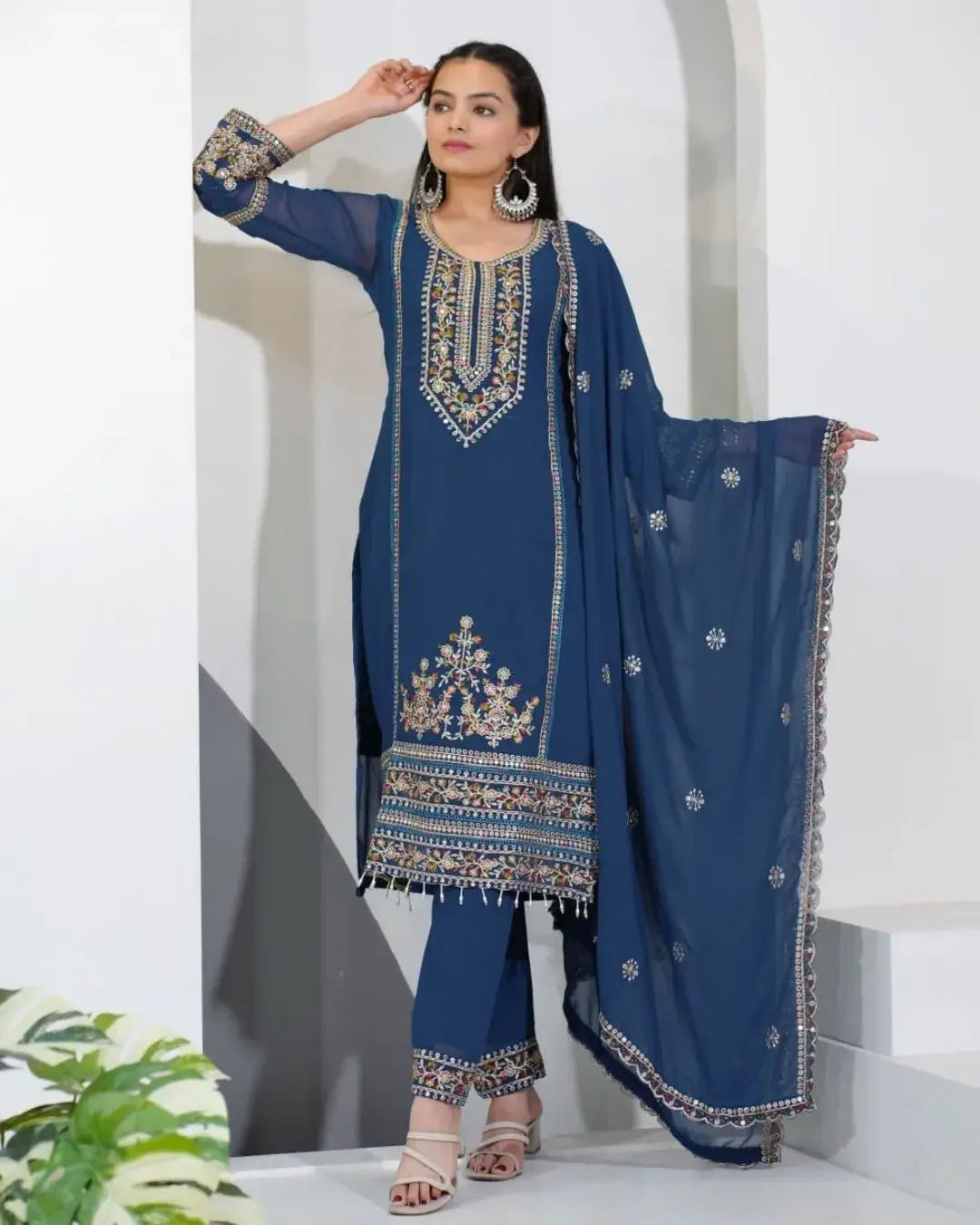 Woman wearing a blue embroidered traditional outfit with a white background
