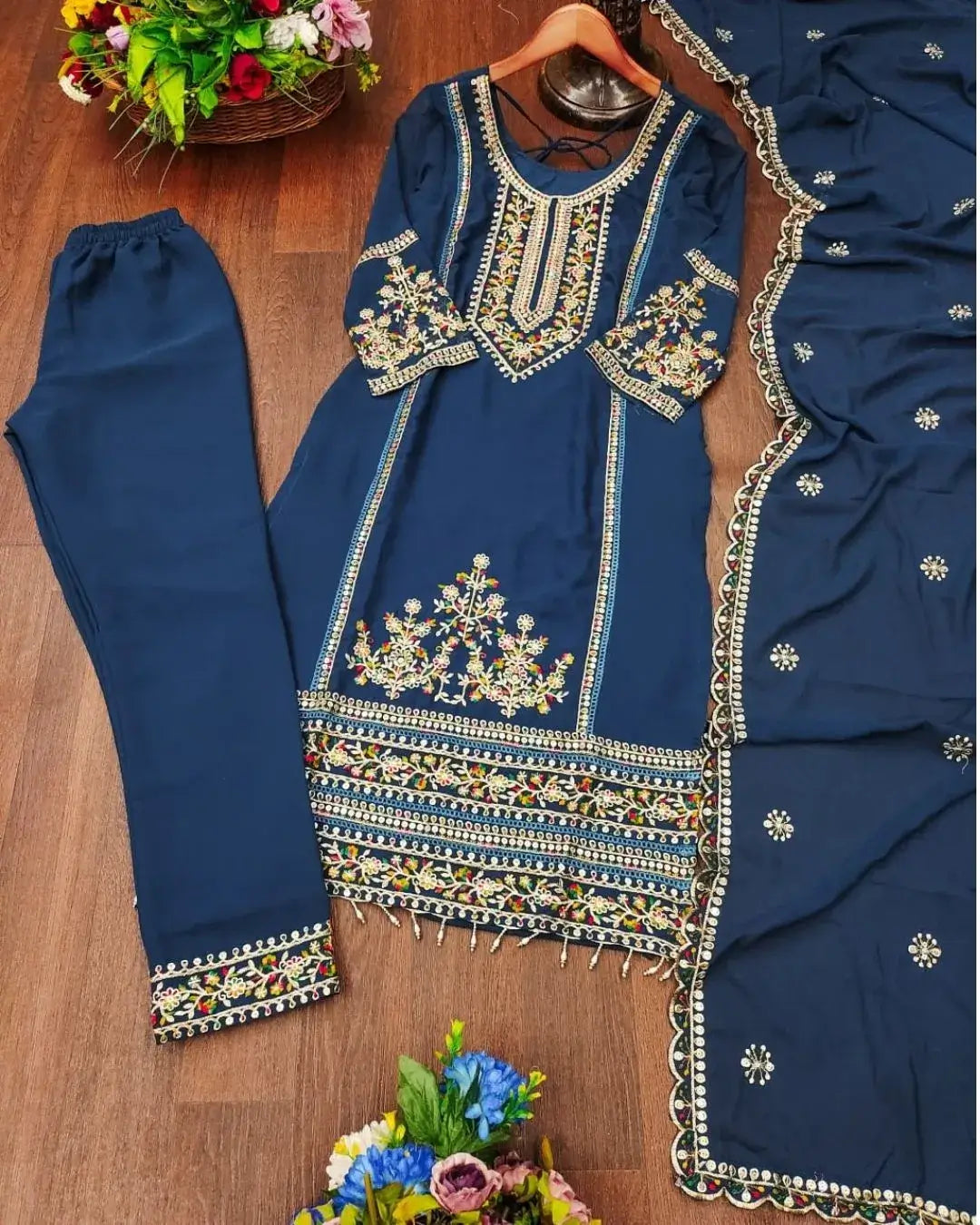 Navy blue embroidered outfit with matching pants on a wooden surface.