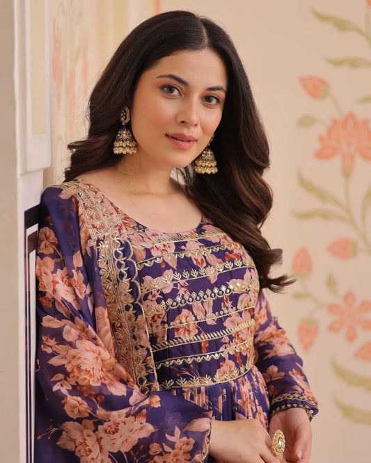 Woman wearing a floral party wear suit set with intricate patterns against a floral background