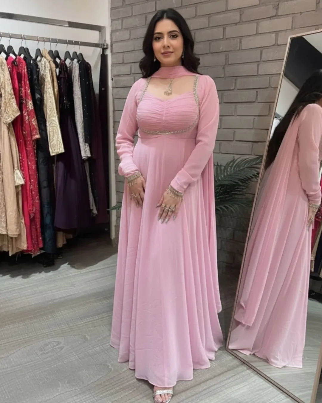 Woman in a pink dress standing in front of a mirror in a clothing store.