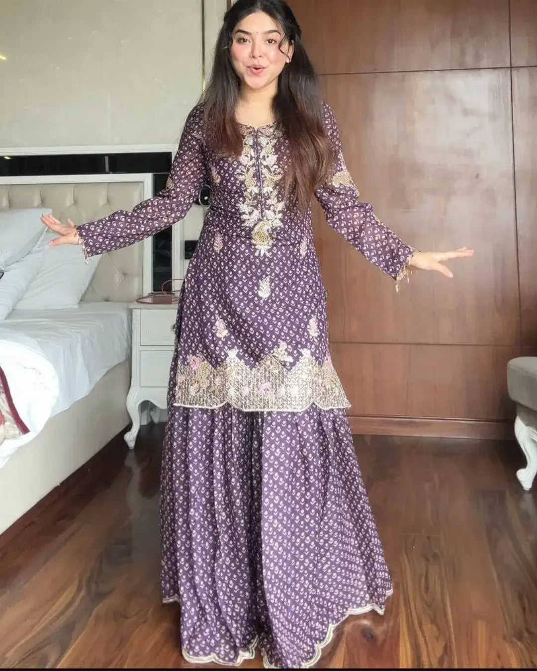 Woman wearing a purple embroidered dress in a bedroom setting