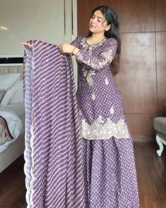 Woman holding a purple and white patterned dupatta in a room with wooden paneling.