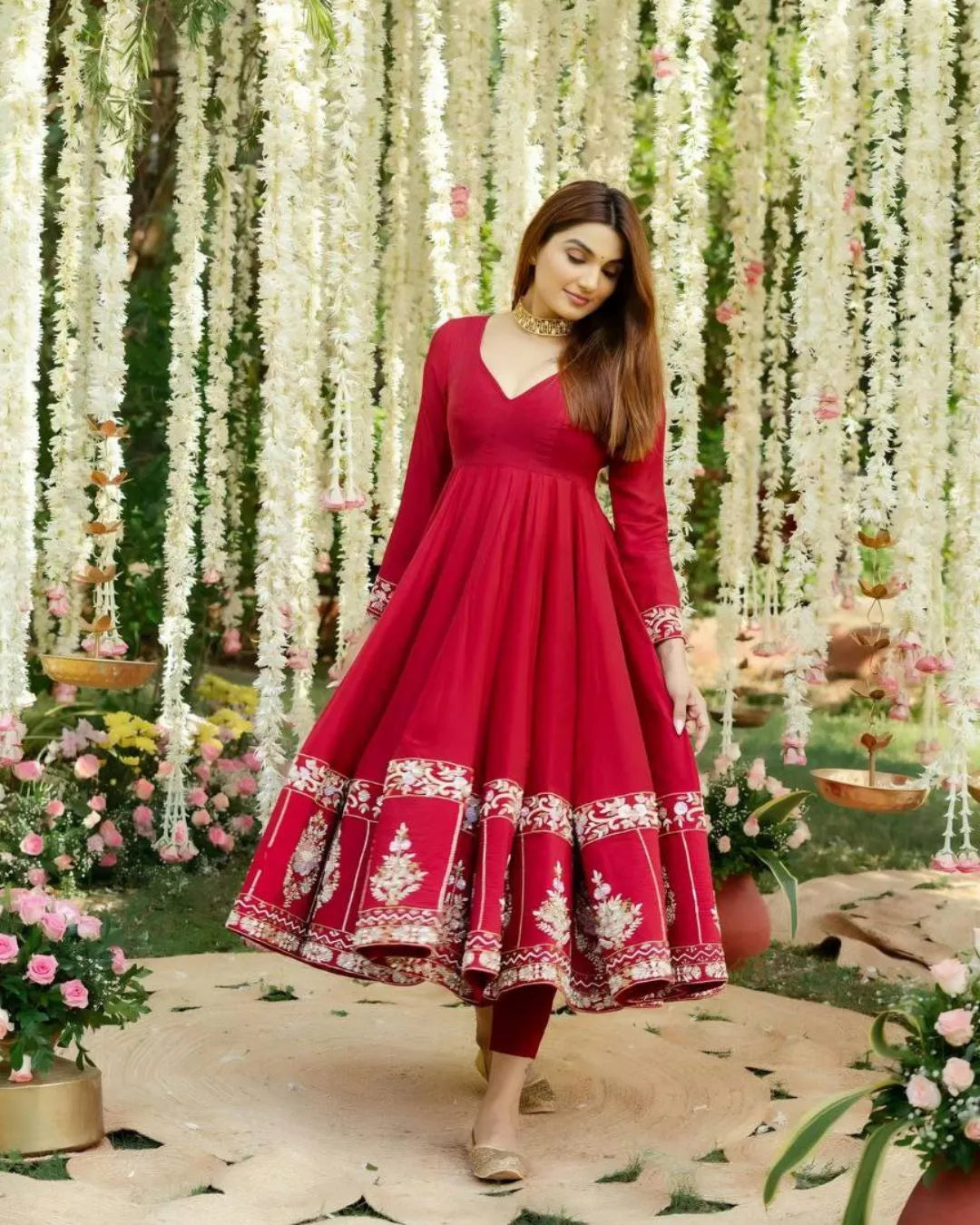 Woman in a red suit with floral decorations in a garden setting