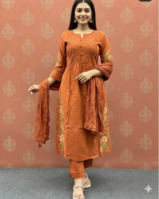 Woman wearing an orange cotton kurti pant dupatta set outfit with a patterned background