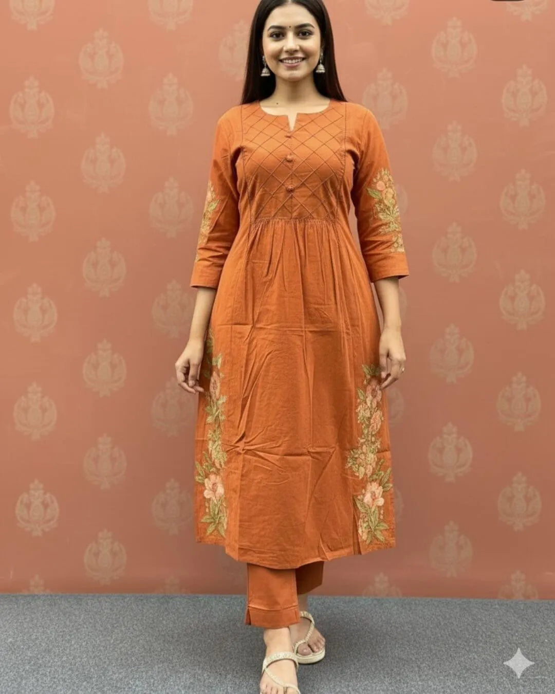 Woman wearing an orange cotton kurti pant dupatta set outfit with a patterned background