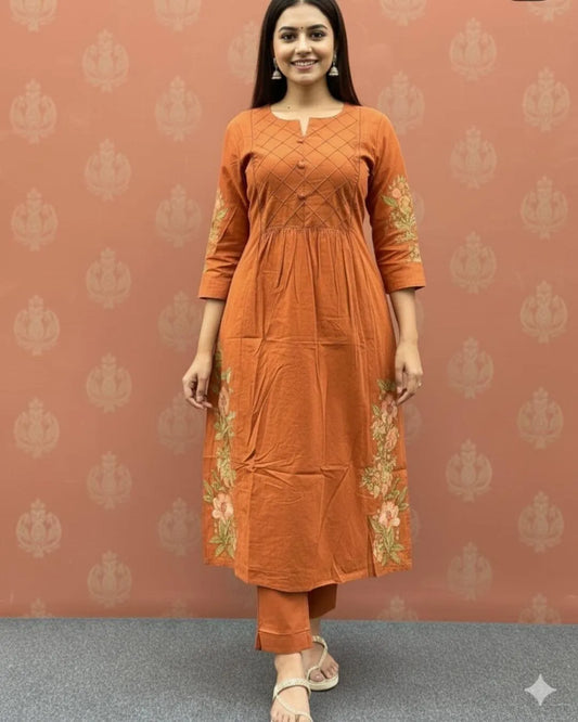 Woman wearing an orange cotton kurti pant dupatta set outfit with a patterned background
