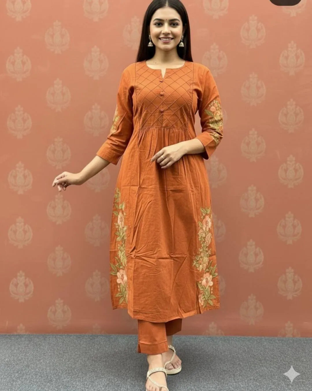Woman wearing an orange cotton kurti pant dupatta set outfit with a patterned background