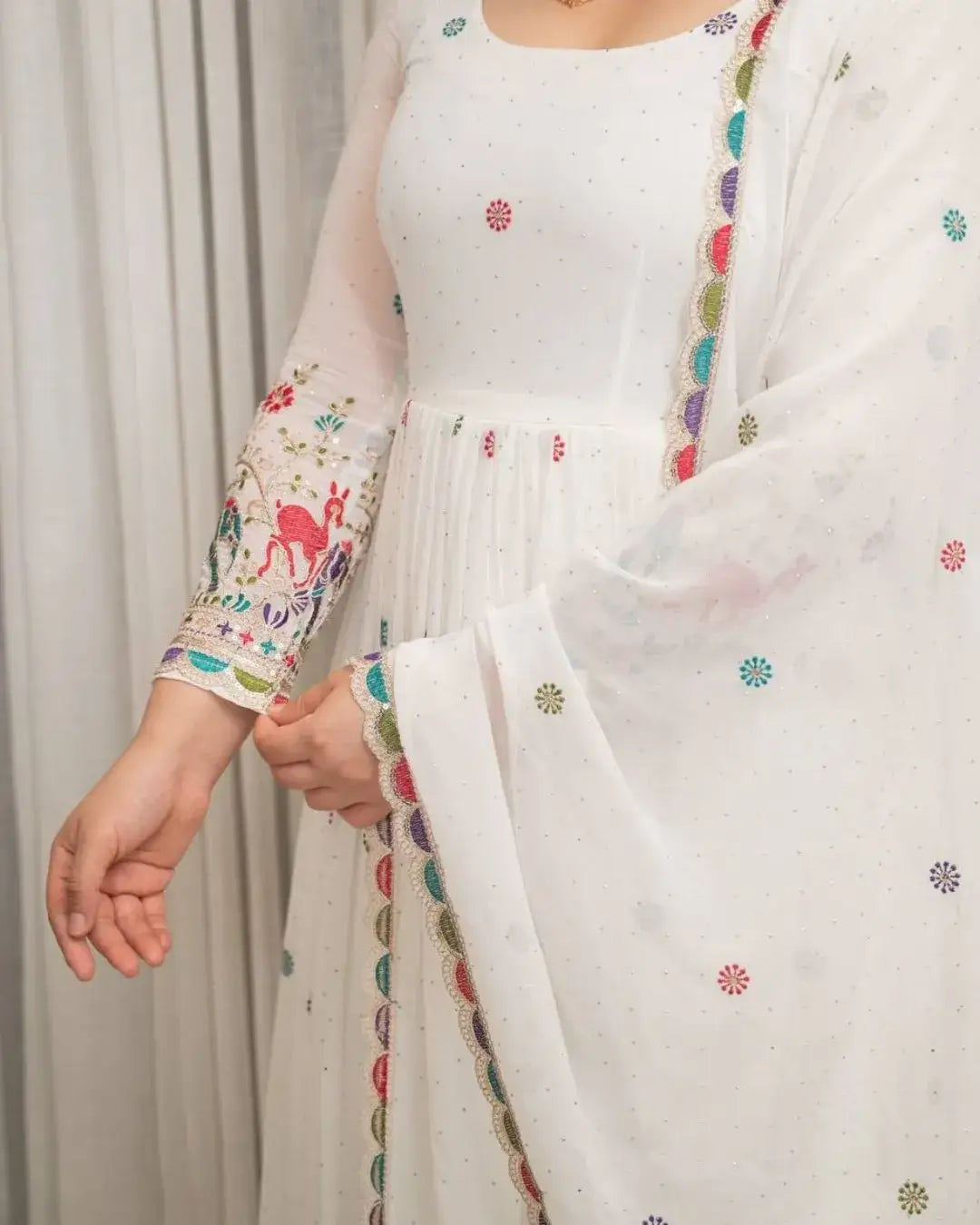 White traditional outfit with colorful embroidery on a plain background