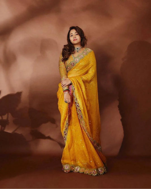Woman wearing a mustard yellow georgette saree with intricate designs