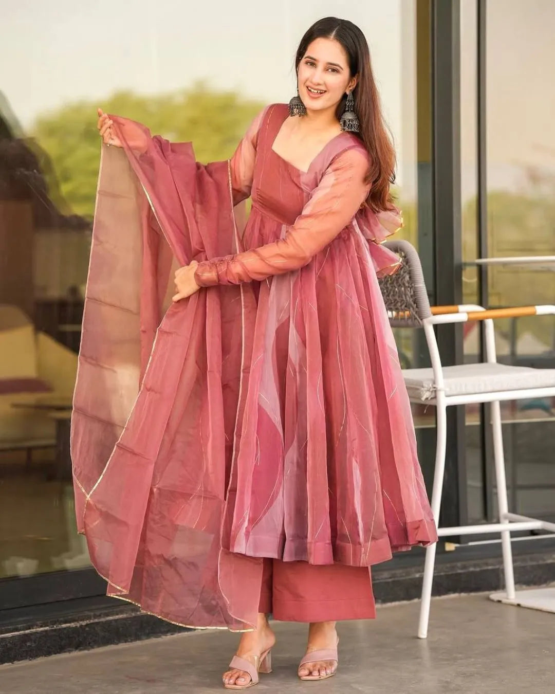 Woman in a pink traditional outfit standing outdoors.