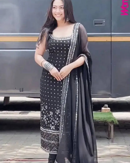 Woman in a black and white traditional outfit standing in front of a bus.