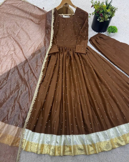 Brown dress with gold trim on a hanger against a neutral background