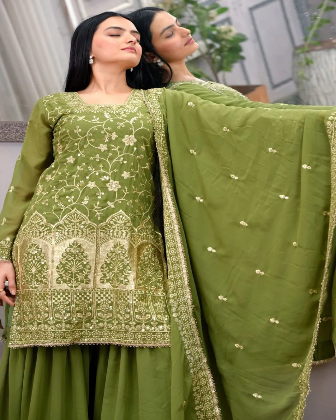 Woman wearing a green embroidered traditional outfit with a matching dupatta.