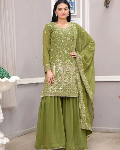 Woman wearing a green embroidered traditional outfit with a plain background