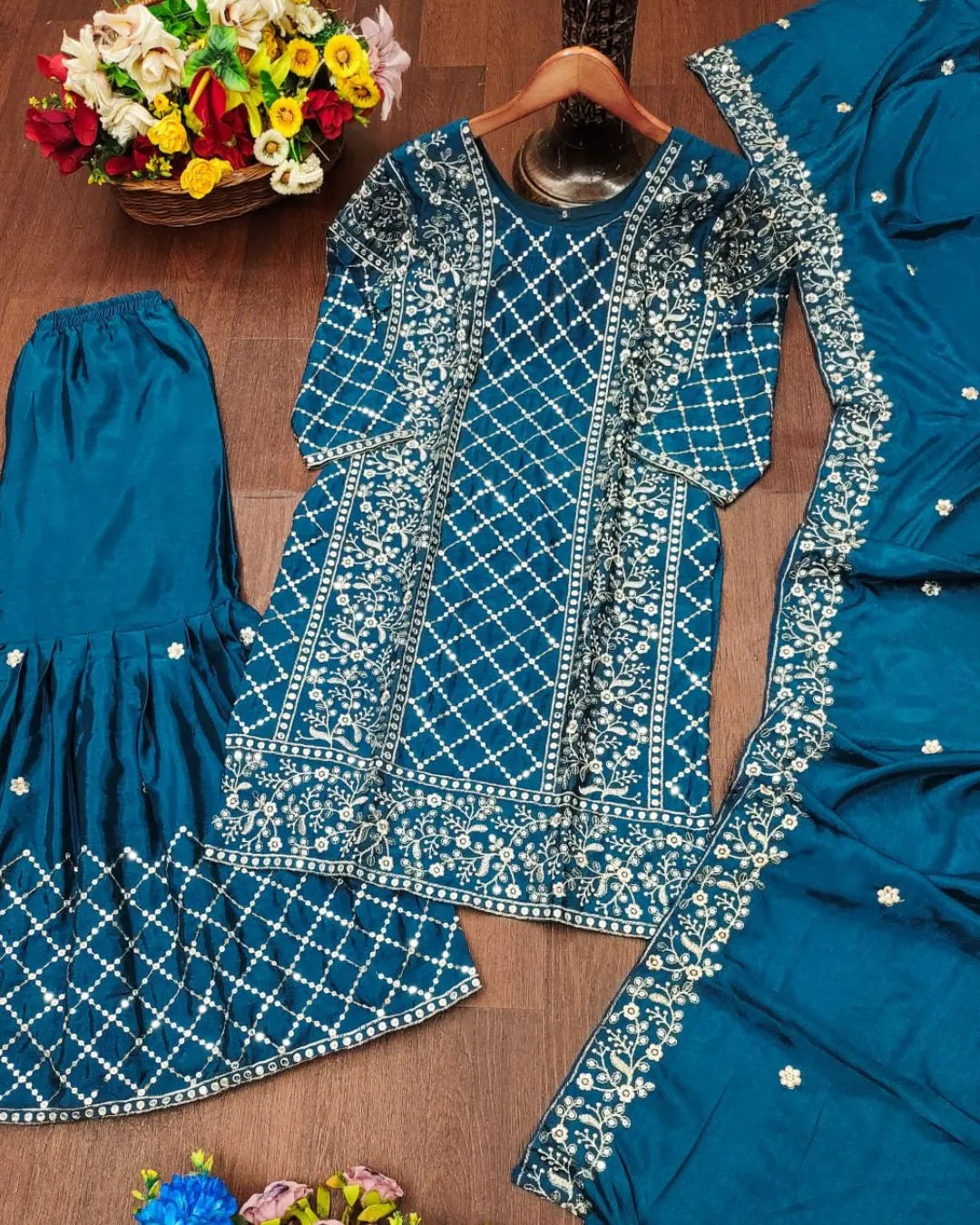 Blue embroidered dress on a wooden surface with flowers in the background