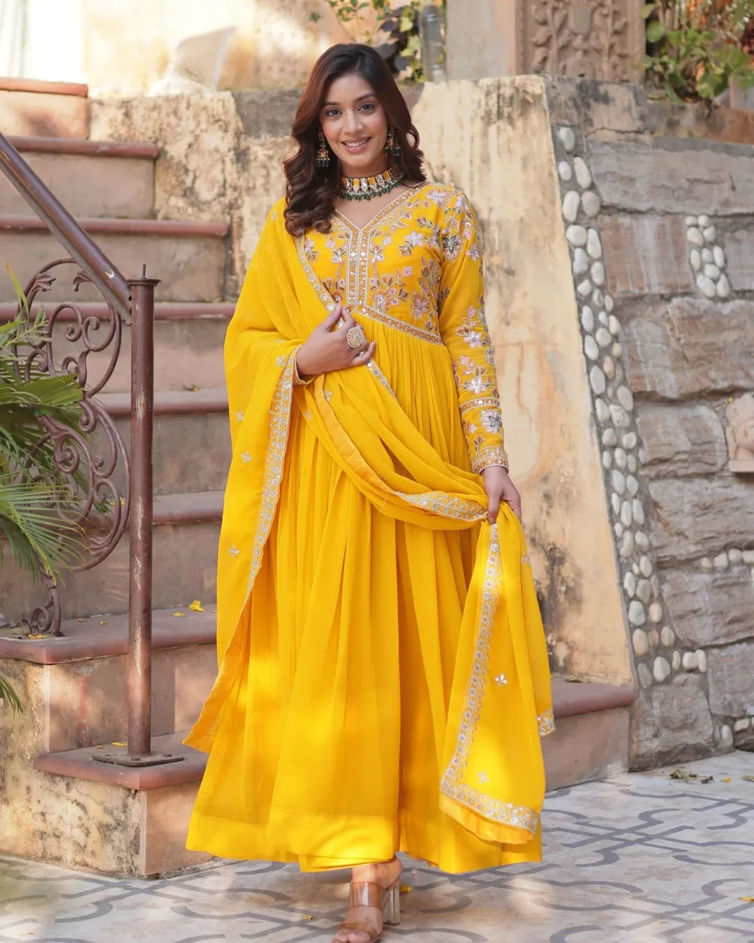 Woman in a yellow traditional outfit standing outdoors.