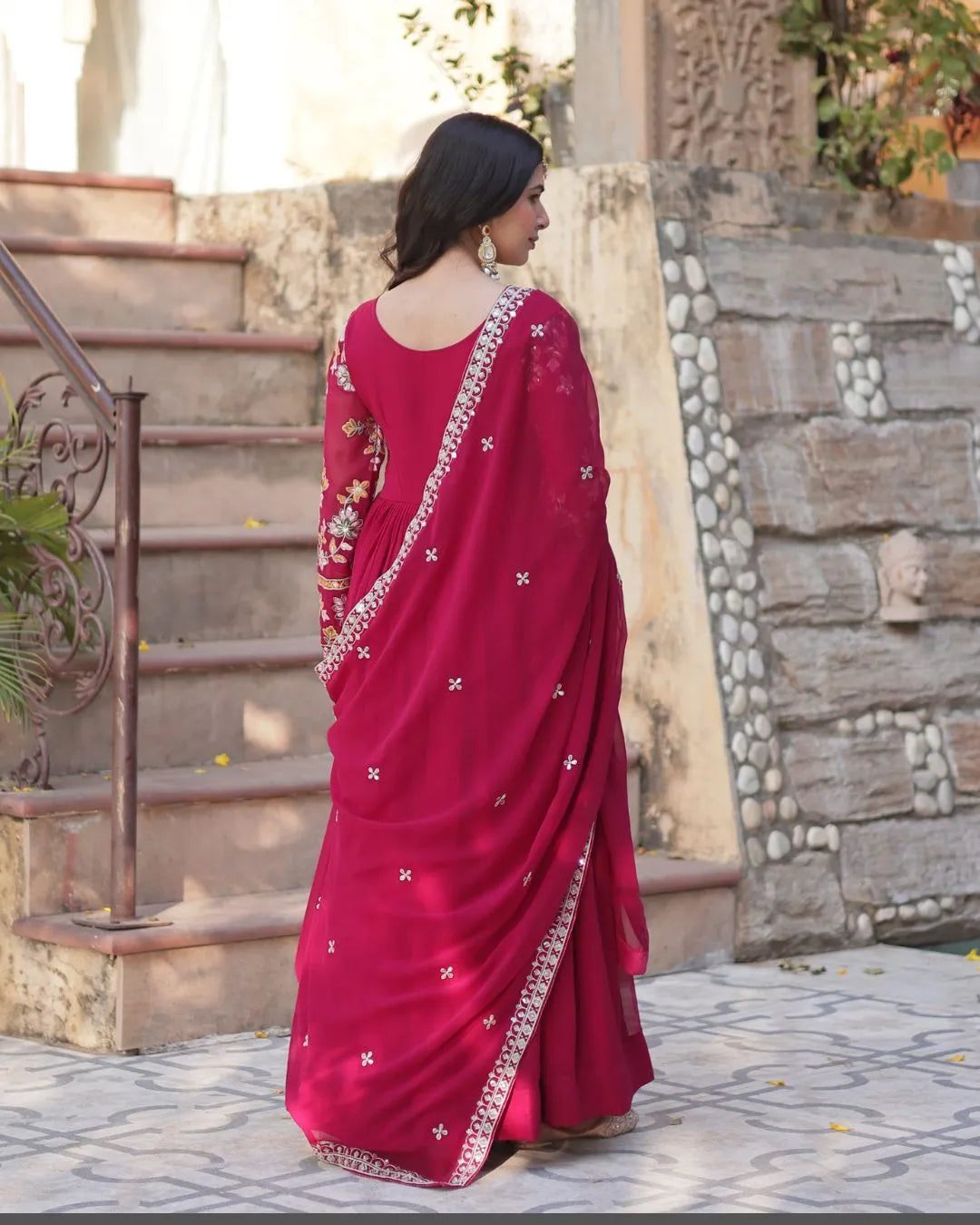 Woman wearing a red suit with white patterns standing outdoors.