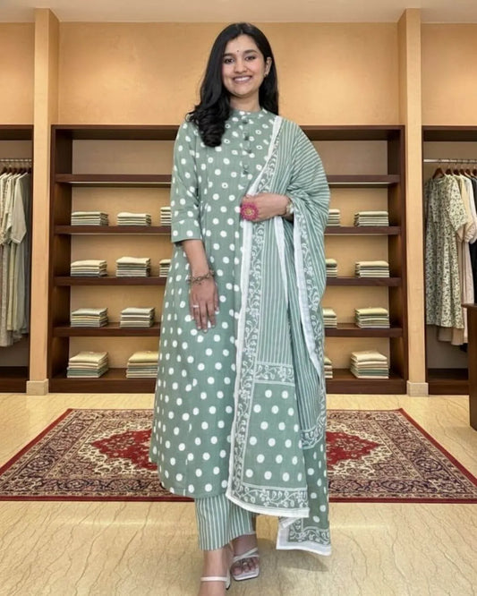 Woman in a green cotton salwar suit set outfit standing in a clothing store.