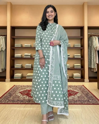 Woman in a green cotton salwar suit set outfit standing in a clothing store.