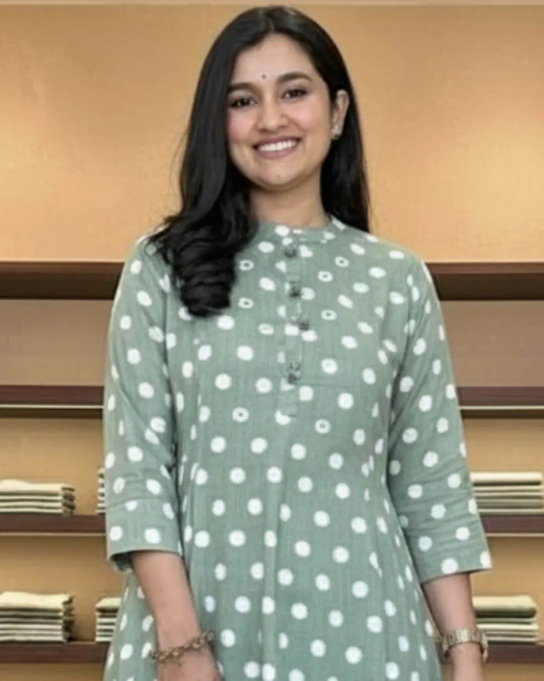 Woman in a green cotton salwar suit set outfit standing in a clothing store.