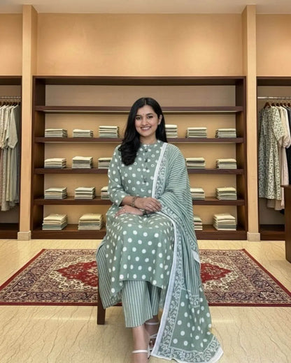Woman in a green cotton salwar suit set outfit standing in a clothing store.