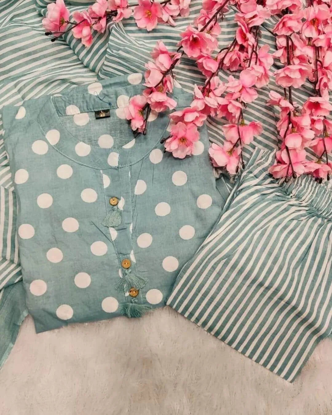 Woman in a green cotton salwar suit set outfit standing in a clothing store.