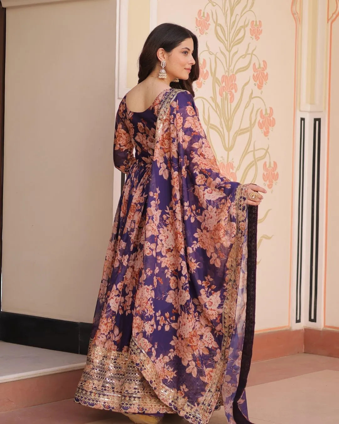 Woman wearing a floral dress with a decorative wall in the background