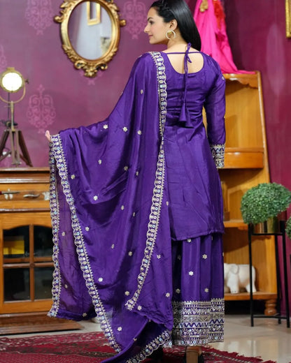 Woman wearing a purple traditional outfit with silver details in a decorated room.