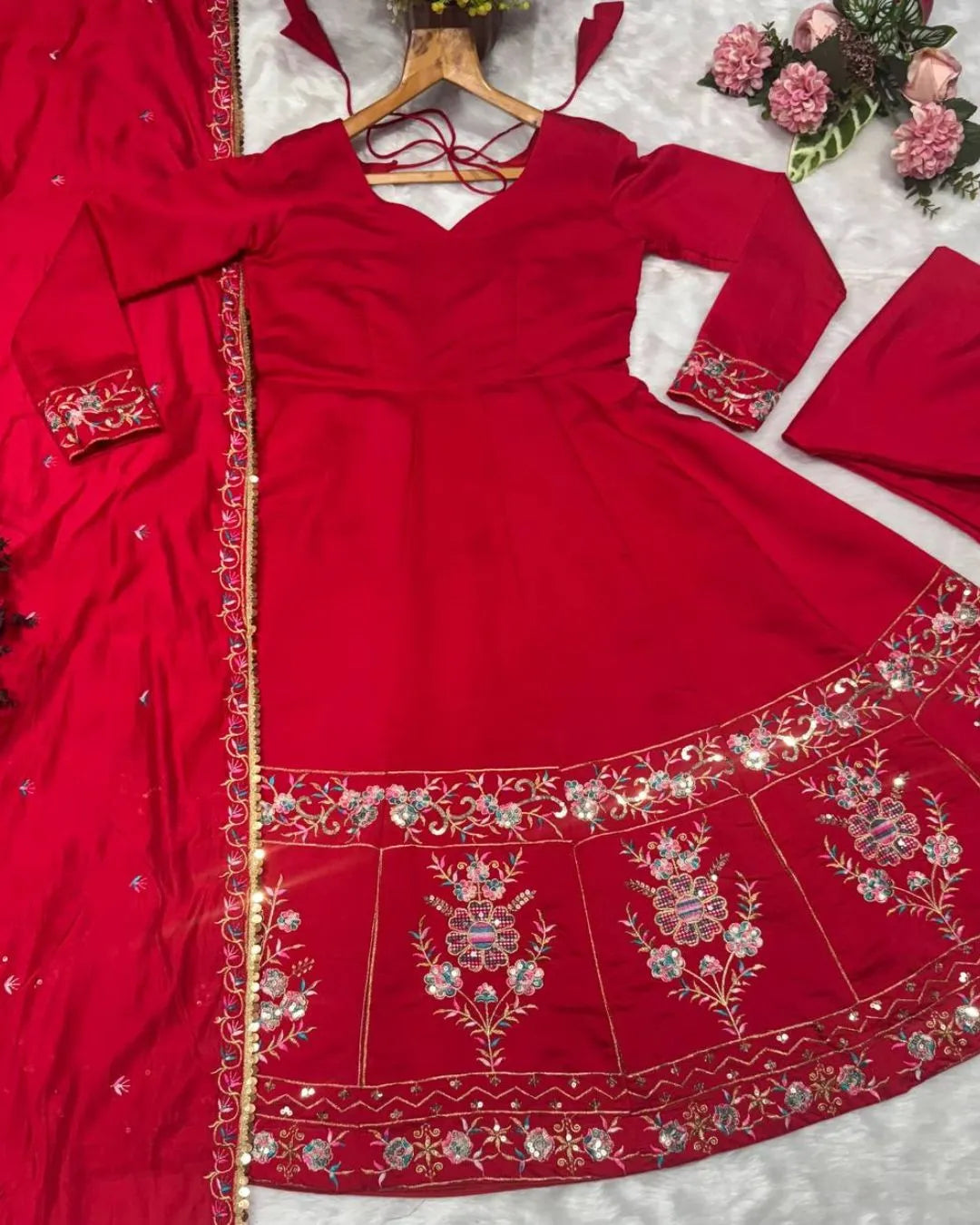 Red embroidered traditional outfit on a white background with flowers.