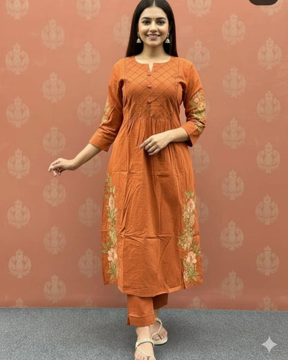 Woman wearing an orange cotton kurti pant dupatta set outfit with a patterned background