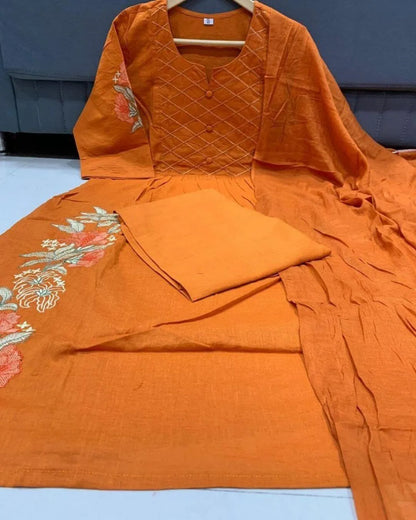 Woman wearing an orange cotton kurti pant dupatta set outfit with a patterned background