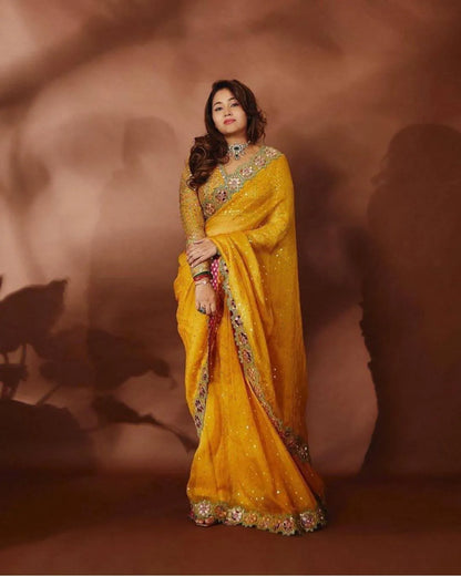 Woman wearing a mustard yellow georgette saree with intricate designs 